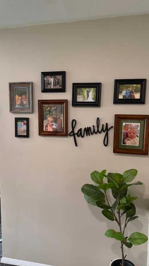 Gallery wall of framed family photos under the word family in the office hallway